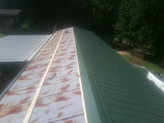 Old rusted panels beside newly installed green metal roofing — Wind Damage Roof Repair by Roofing Brothers in Gunter