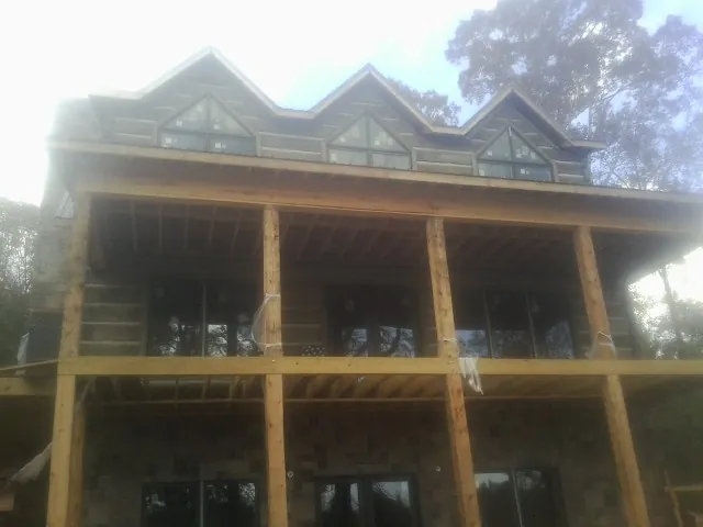 Dormers and porch framing on a large log home under construction — Roof Coating work by our crew in Gunter