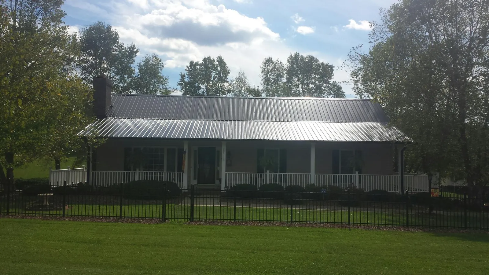 Gray metal roof on a brick ranch with a full width front porch — Gutter Guard Installation work by our crew in Gunter