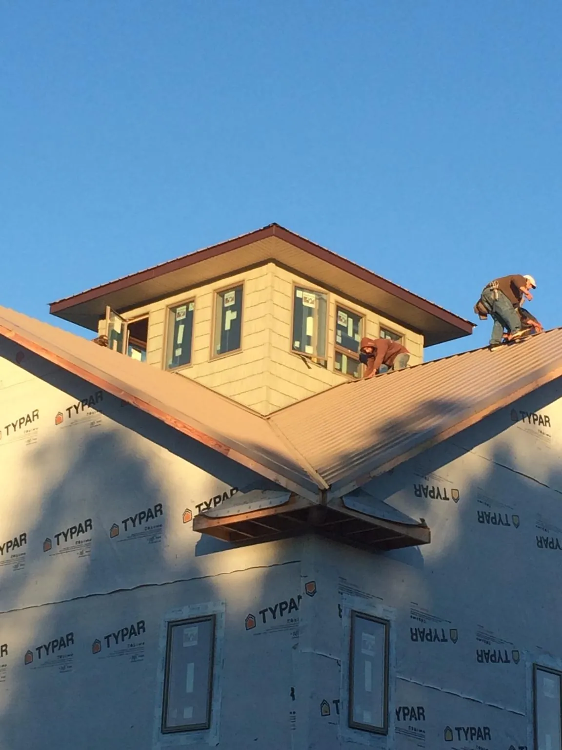 Roofers working around a rooftop cupola on a new metal roof at sunset — Roof Waterproofing in Gunter by Roofing Brothers